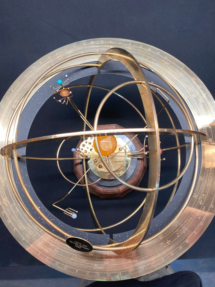 Overhead view of the Tower Orrery showing the engraved brass calendar ring and the upper half of the brass full armillary sphere. The inner solar system is depicted showing the Sun in orange calcite , the earth moon system.