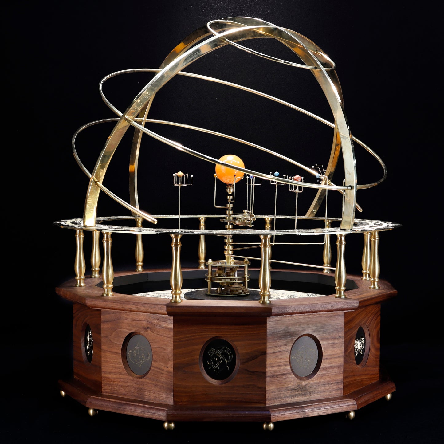 A premium museum, gallery quality, grand orrery with a solid brass calendar ring, brass planets and moons, and a half armillary sphere on top, all mounted on a hand-oiled black walnut wood base. Twelve panel depict each sign of the zodiac.