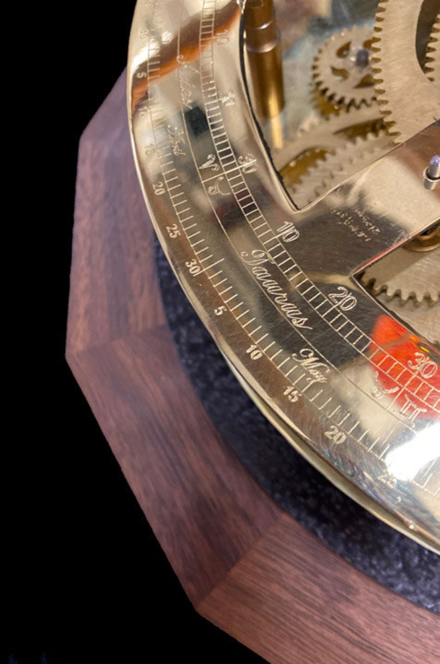 Close up photograph of the Renaissance Orrery from Science Art depicting the solid walnut base and the brass engraved calendar ring. The calendar ring is engraved with the 12 zodiacal symbols and depicts the months of the year.