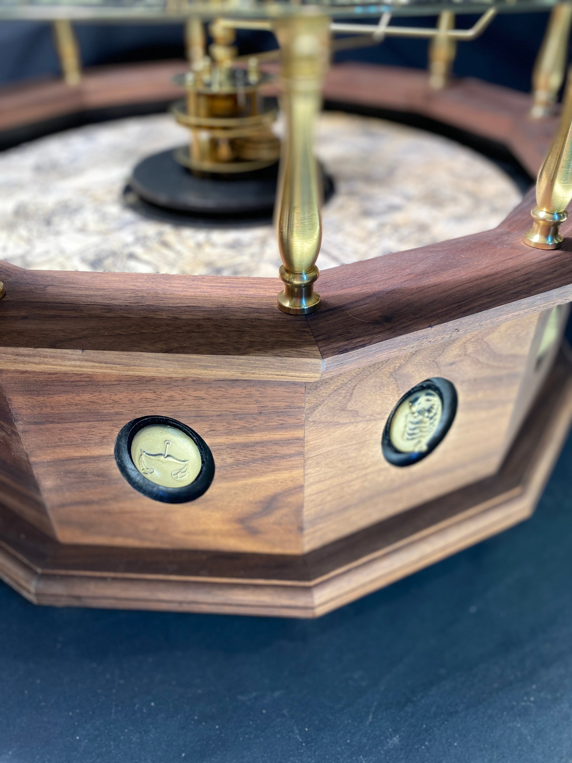 Depicts a close up view of the bas relief zodiacal planets on the hardwood base of the museum quality grand orrery.