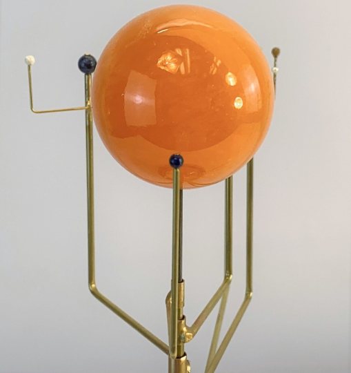 Close up of orrery with orange calcite stone sphere